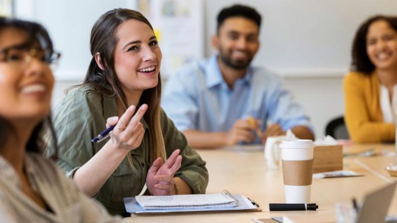 three people sat around a table in a meeting